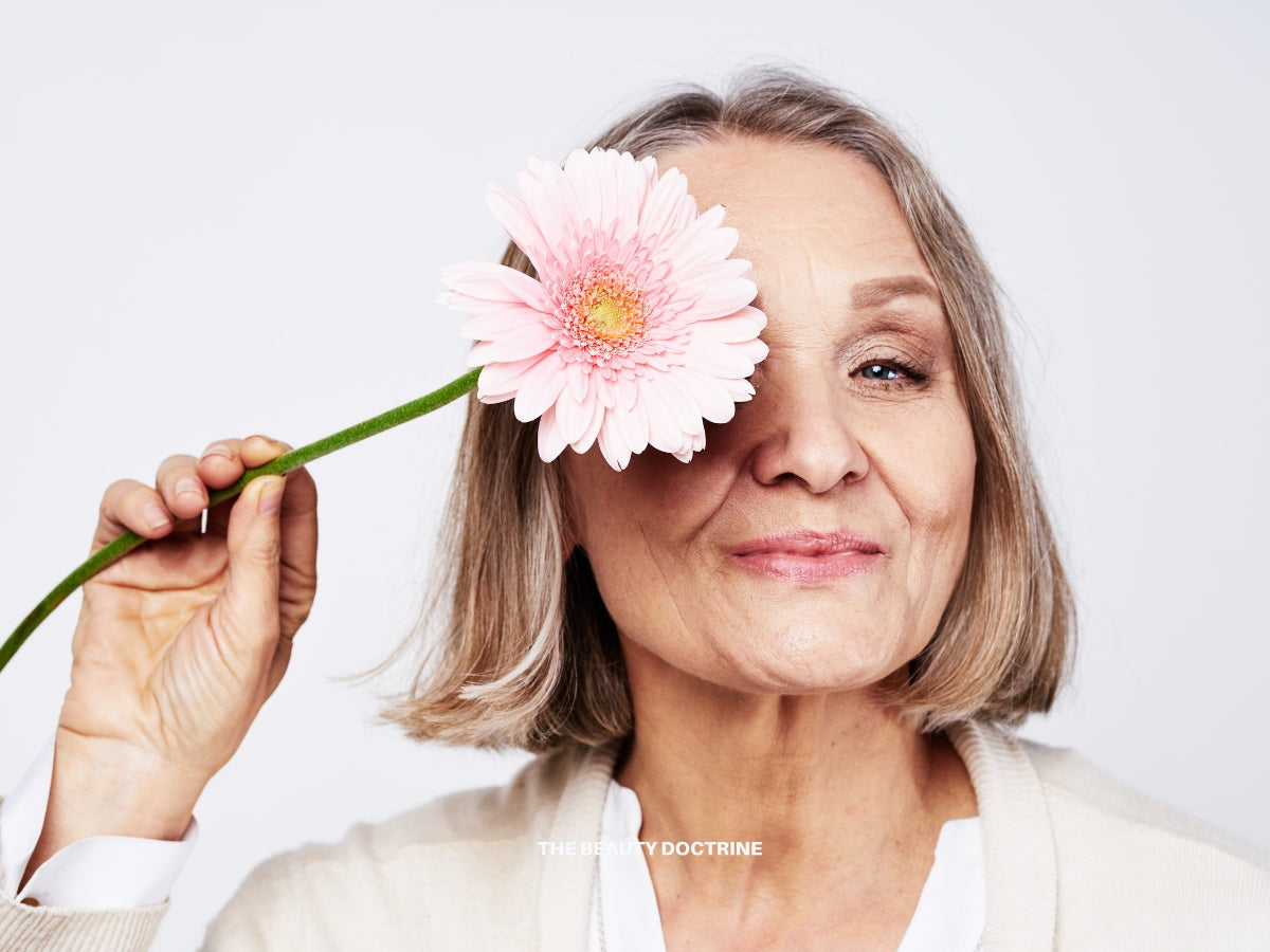 Woman examining skin changes during menopause — collagen loss, dryness, and aging explained by The Beauty Doctrine