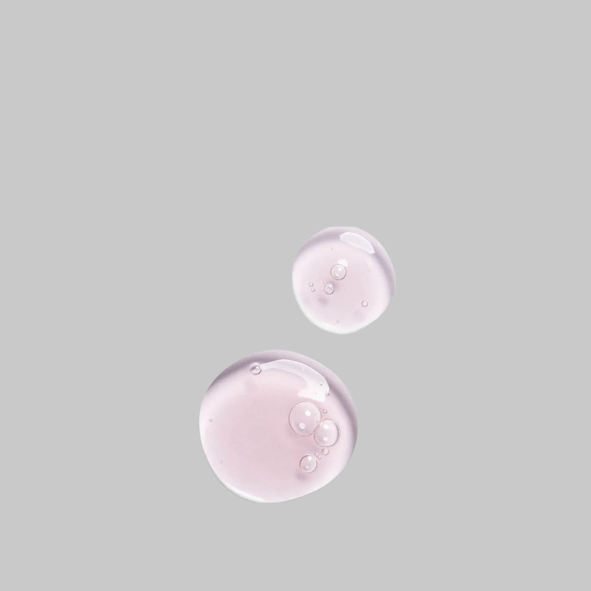 Two pale pink drops of Bloomeffects Black Tulip Regenerative Serum showing its translucent texture.