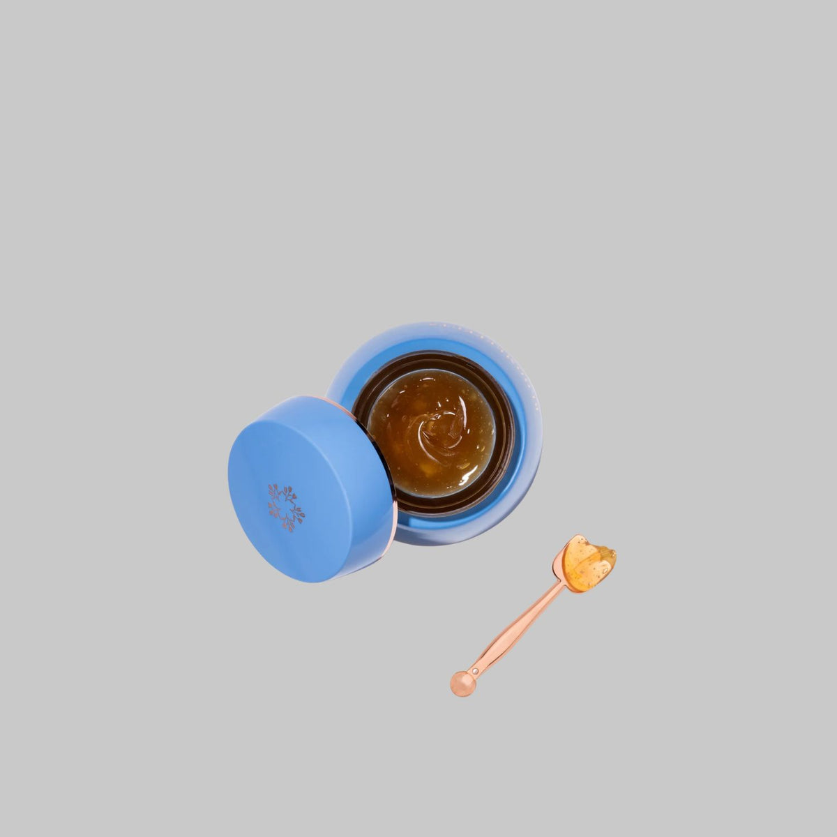 Open jar of Bloomeffects Royal Tulip Moisturizing Nectar showing golden balm texture beside a small spatula.