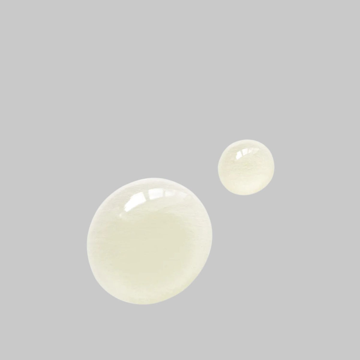 Two pale yellow drops of Bloomeffects Royal Tulip Vitamin C Facial Oil showing its glossy texture.