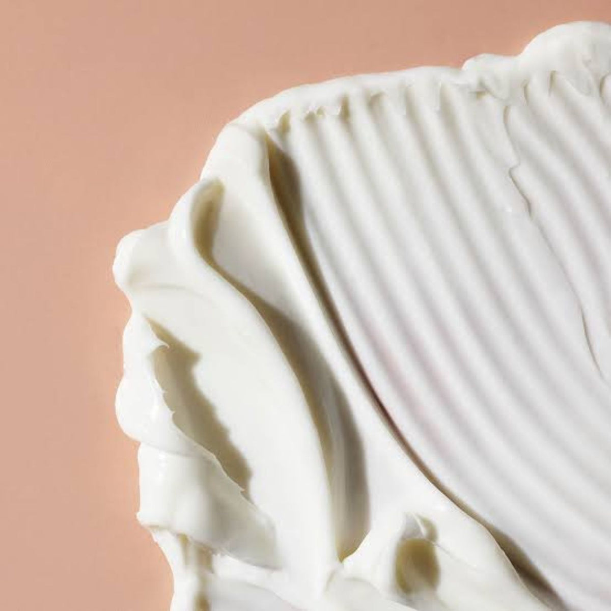 Close-up of Wildling Moonbounce Plumping Moisturizer’s rich white cream texture on a peach background