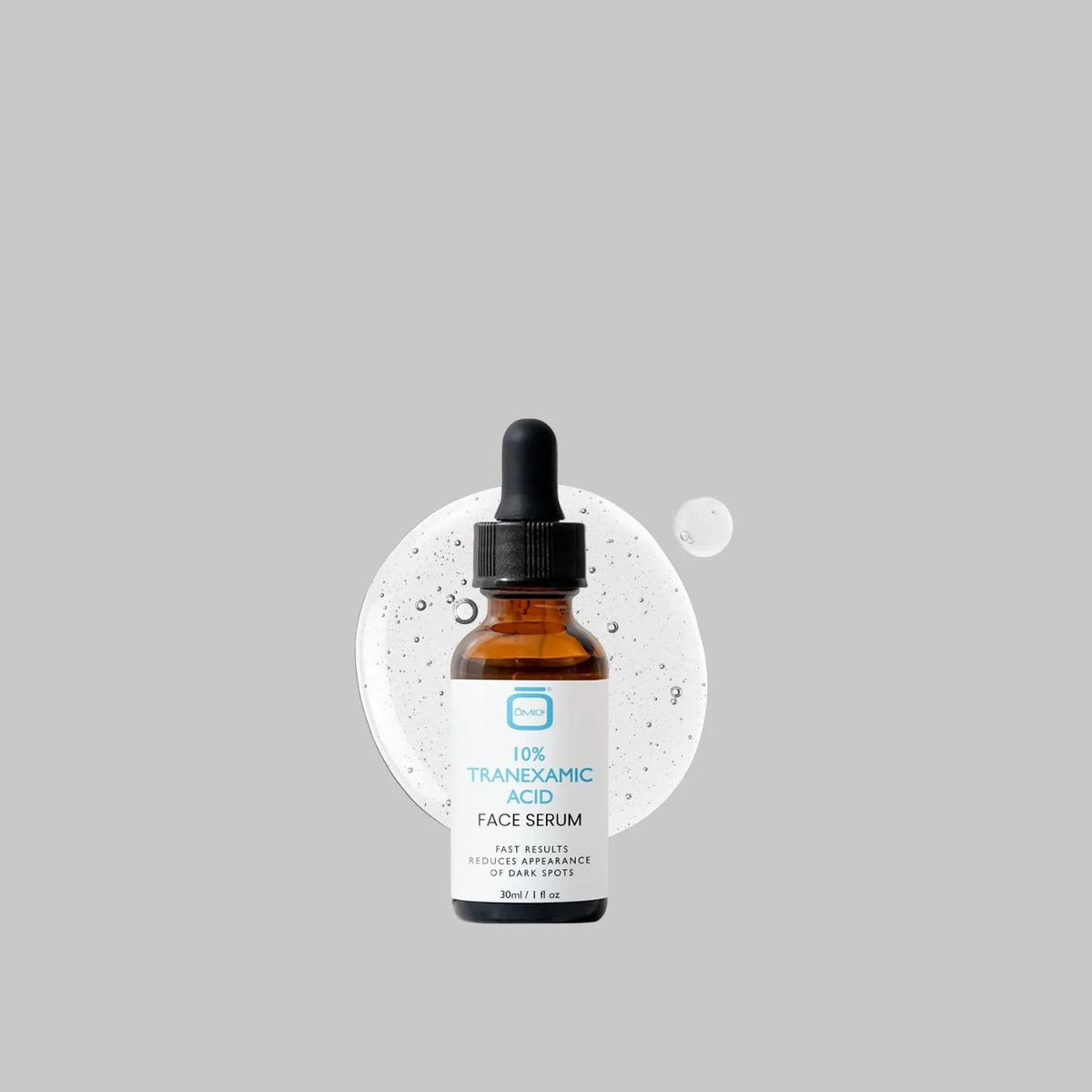 bottle with serum swatch: OMIC+ 10% Tranexamic Acid Face Serum dropper bottle with a clear serum swatch and bubbles behind it.