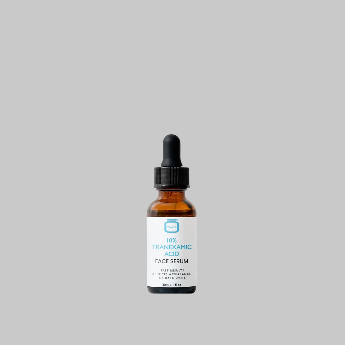 bottle on gray background: OMIC+ 10% Tranexamic Acid Face Serum in a 30 ml amber glass bottle with a black dropper on a gray background.