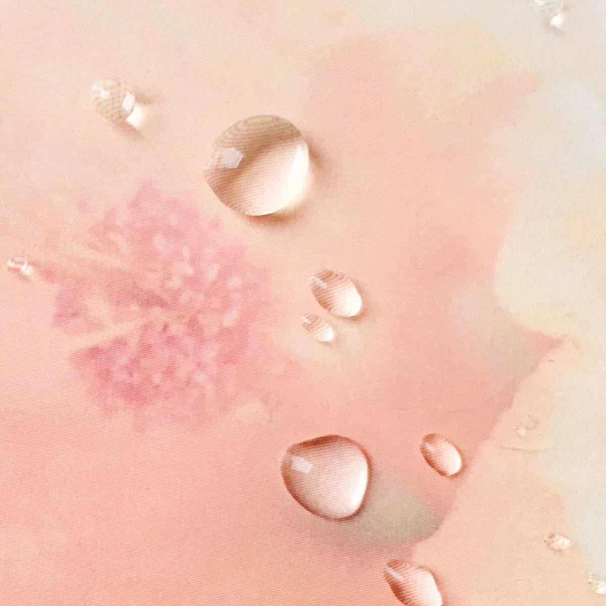 Clear serum droplets on a soft pink background, showing the watery texture of TAHNYC Amino Sugar Serum Water
